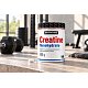 Creatine Monohydrate – muž v posilovně, dóza kreatinu na podlaze u činek
